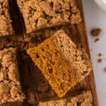 Overhead image of pumpkin crumb cake cut into squares. One square is turned on its side.