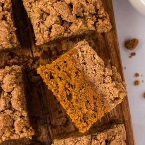 Overhead image of pumpkin crumb cake cut into squares. One square is turned on its side.
