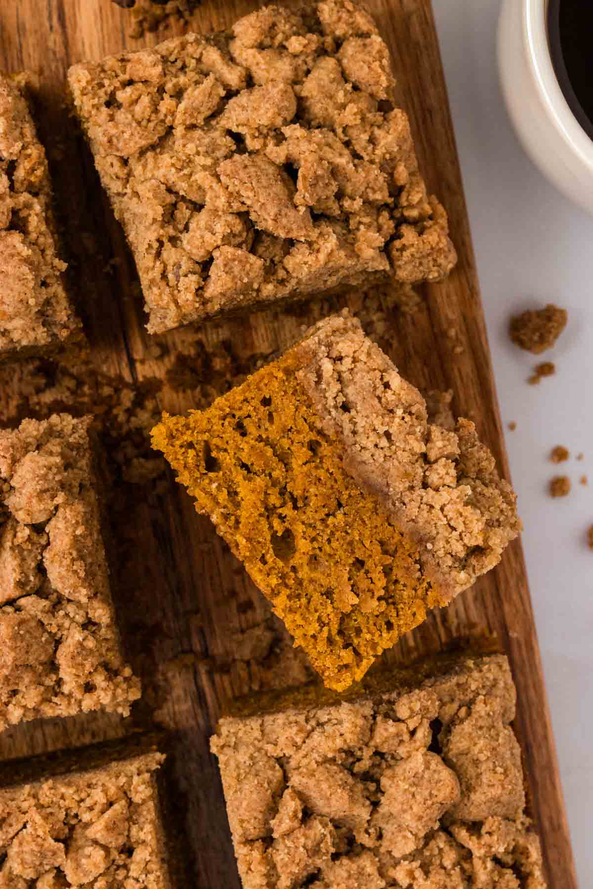 Overhead image of pumpkin crumb cake cut into squares. One square is turned on its side.