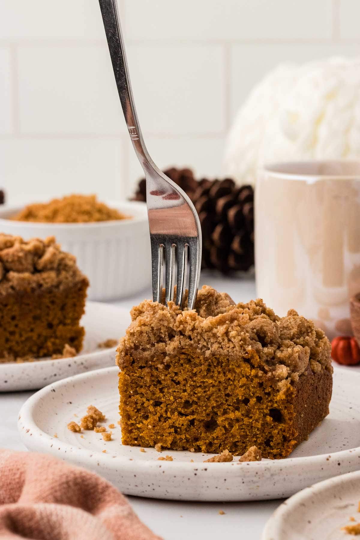A fork plunging into a slice of pumpkin crumb cake.