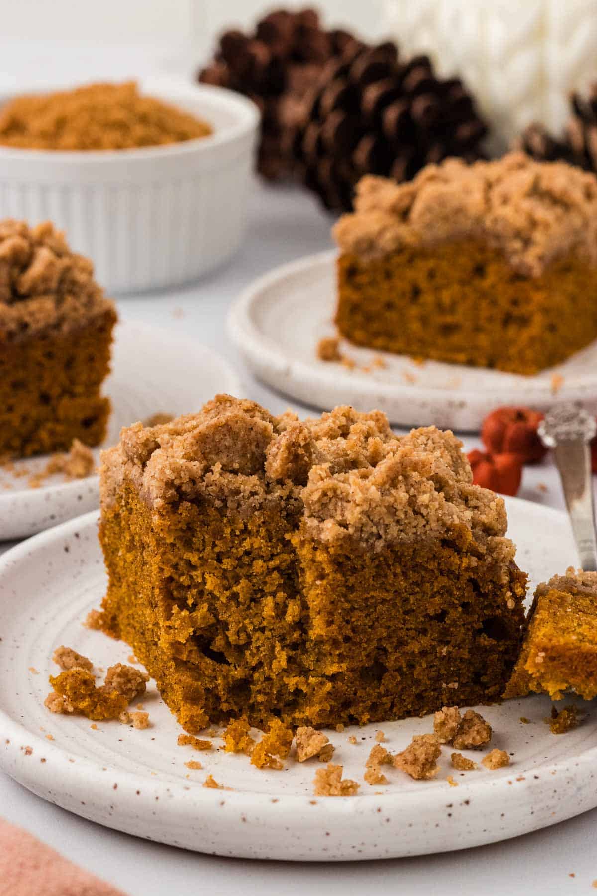 Pumpkin crumb cake on a plate with a bite taken out of it.