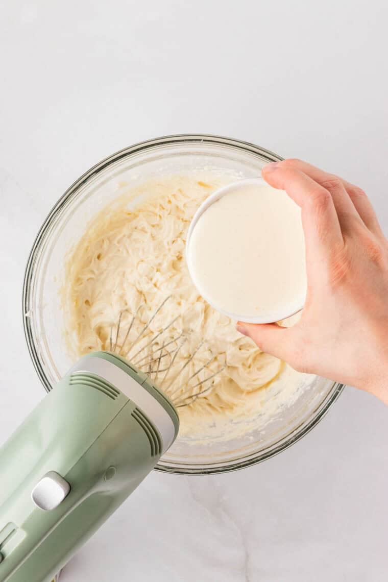 Adding heavy cream to a mixture of Cream cheese, Greek yogurt, powdered sugar, and vanilla.