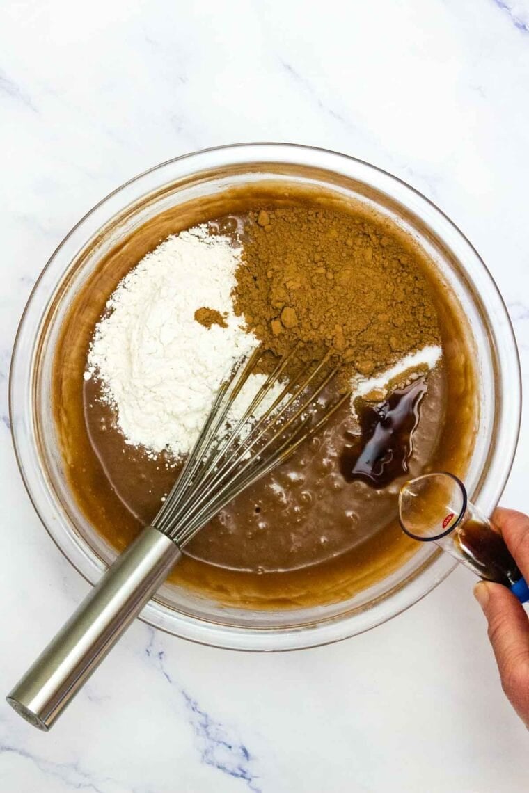 Adding GF flour, cocoa powder, and vanilla to Nutella brownie batter.