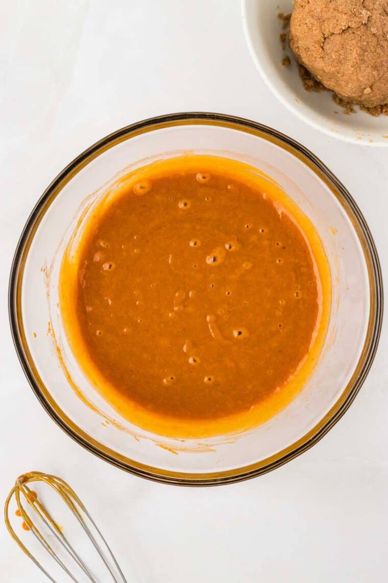 Pumpkin puree, sugar, oil, eggs, and vanilla mixed together in a bowl.