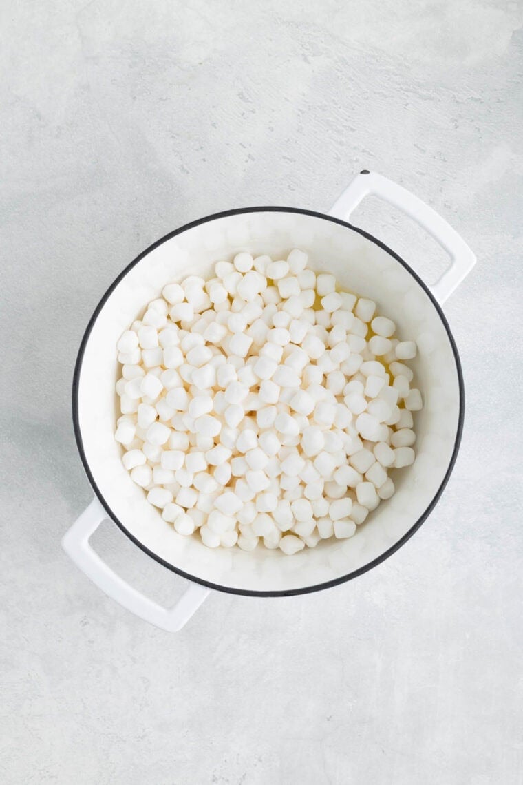 Adding mini marshmallows to a pot with melted butter.