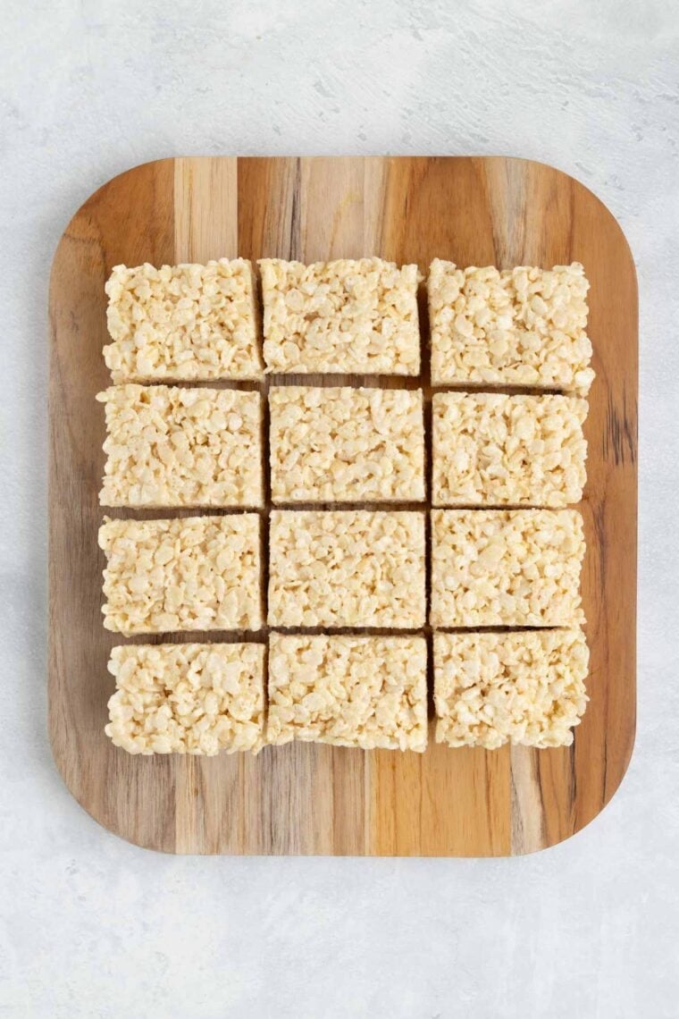 Rice Krispies treats cut into rectangles on a cutting board.