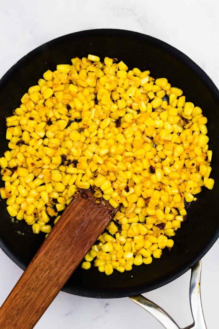 Saut&eacute;ing seasoned corn and chopped chilis in adobo.