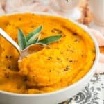 A spoon scooping up butternut squash puree from a dish with text overlay that says "Mashed Butternut Squash".