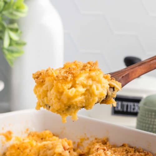 Close-up image of a wooden spoon scooping some gluten free mac and cheese out of a casserole dish.