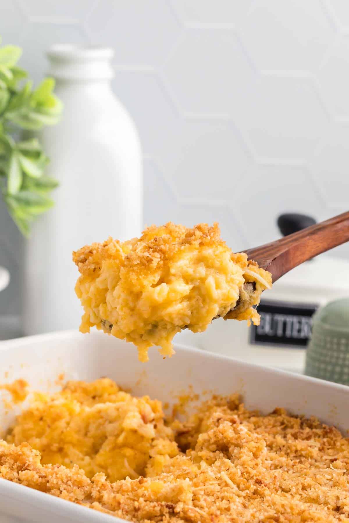 Close-up image of a wooden spoon scooping some gluten free mac and cheese out of a casserole dish.