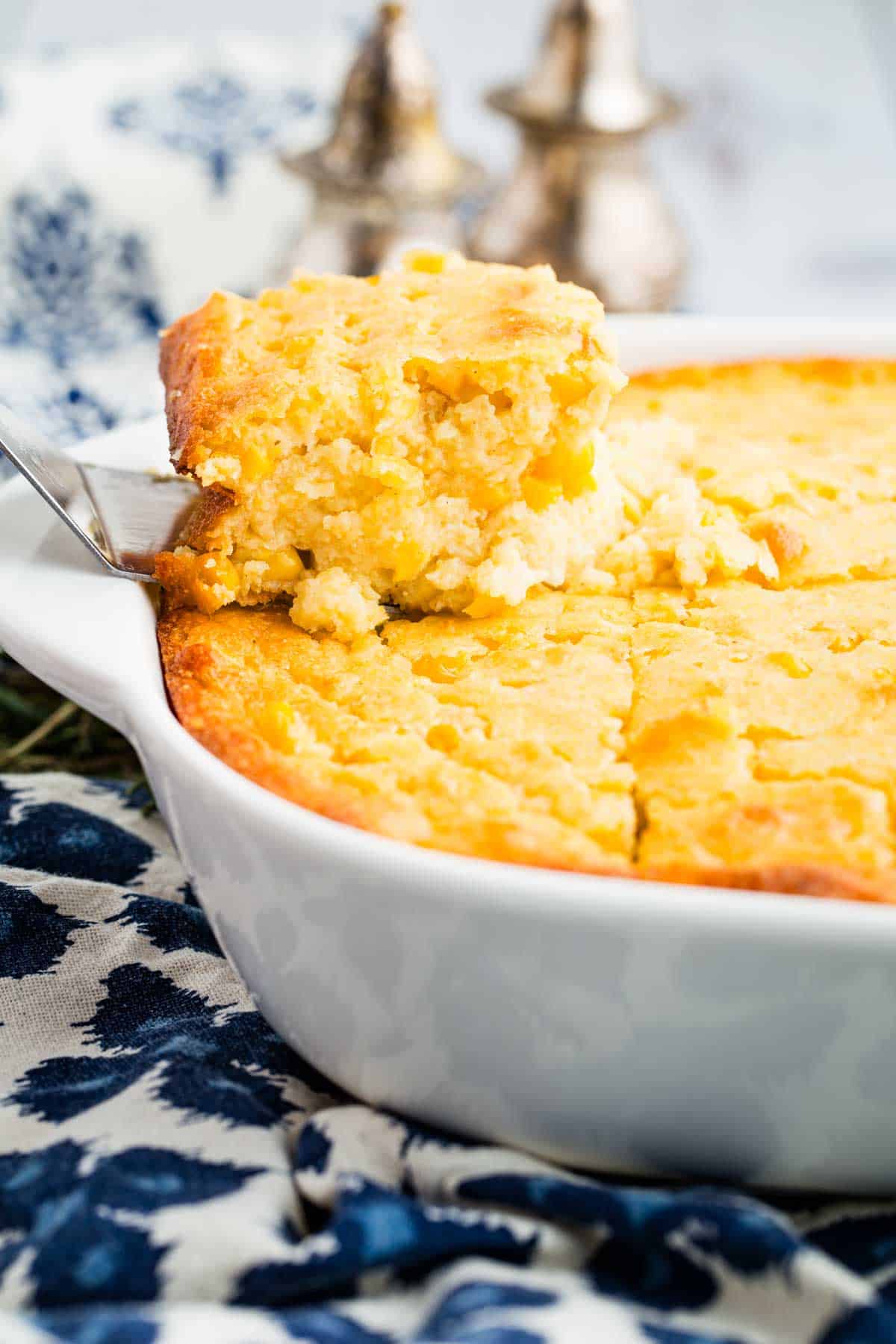 This wildly easy gluten-free corn casserole combines sweet and savory goodness with a creamy texture that’s guaranteed to be a hit. A spatula removing a slice of corn casserole from a baking dish.