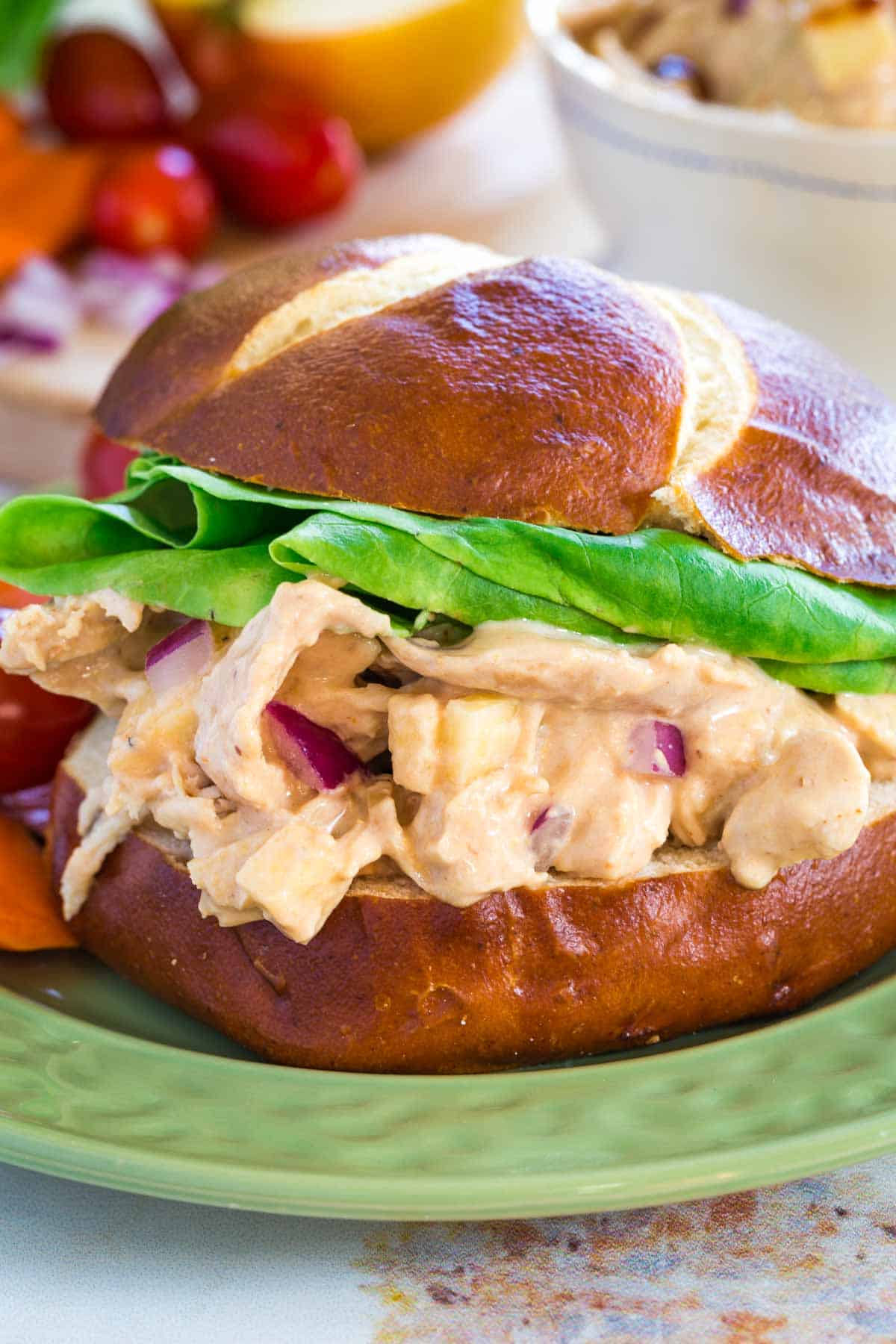 A closeup of creamy BBQ chicken salad on a bun with lettuce.