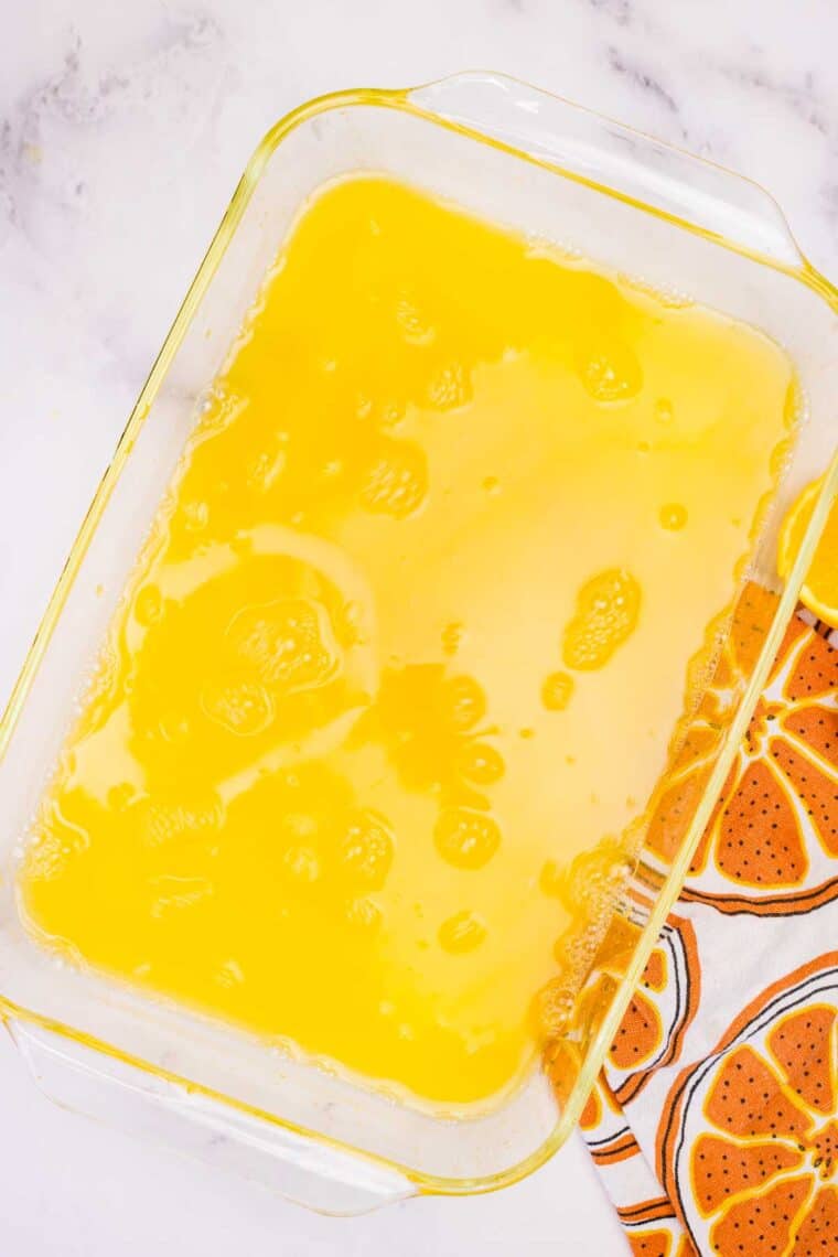 Orange jello poured into a baking dish.