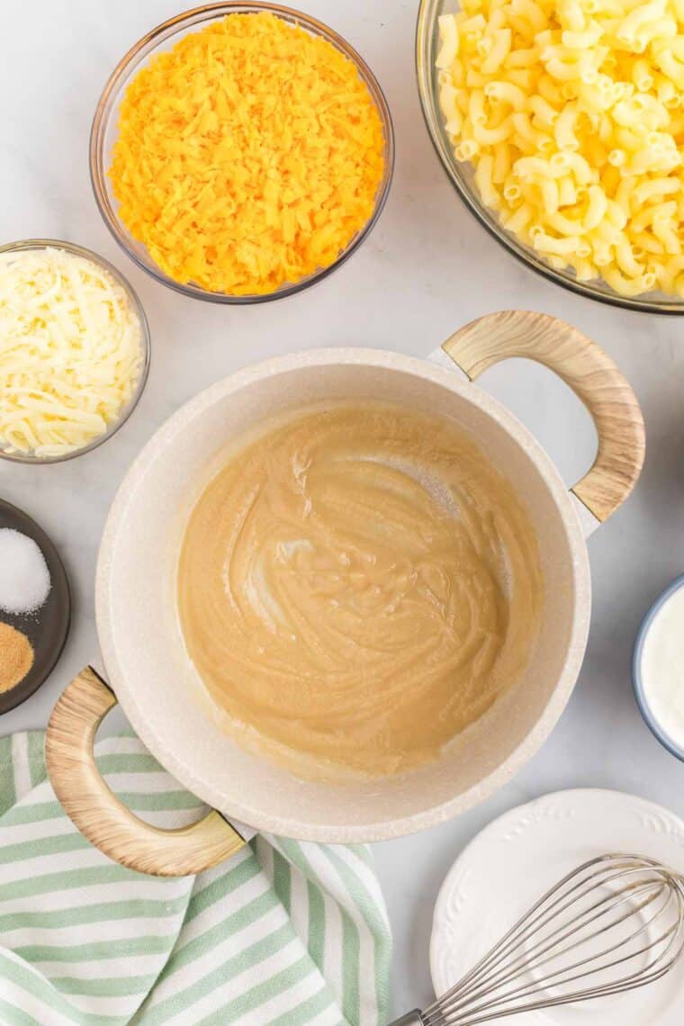 This gluten-free mac and cheese is so creamy and satisfying, with a crunchy breadcrumb topping that takes it over the edge! A roux in a pot surrounded by ingredients for mac and cheese.