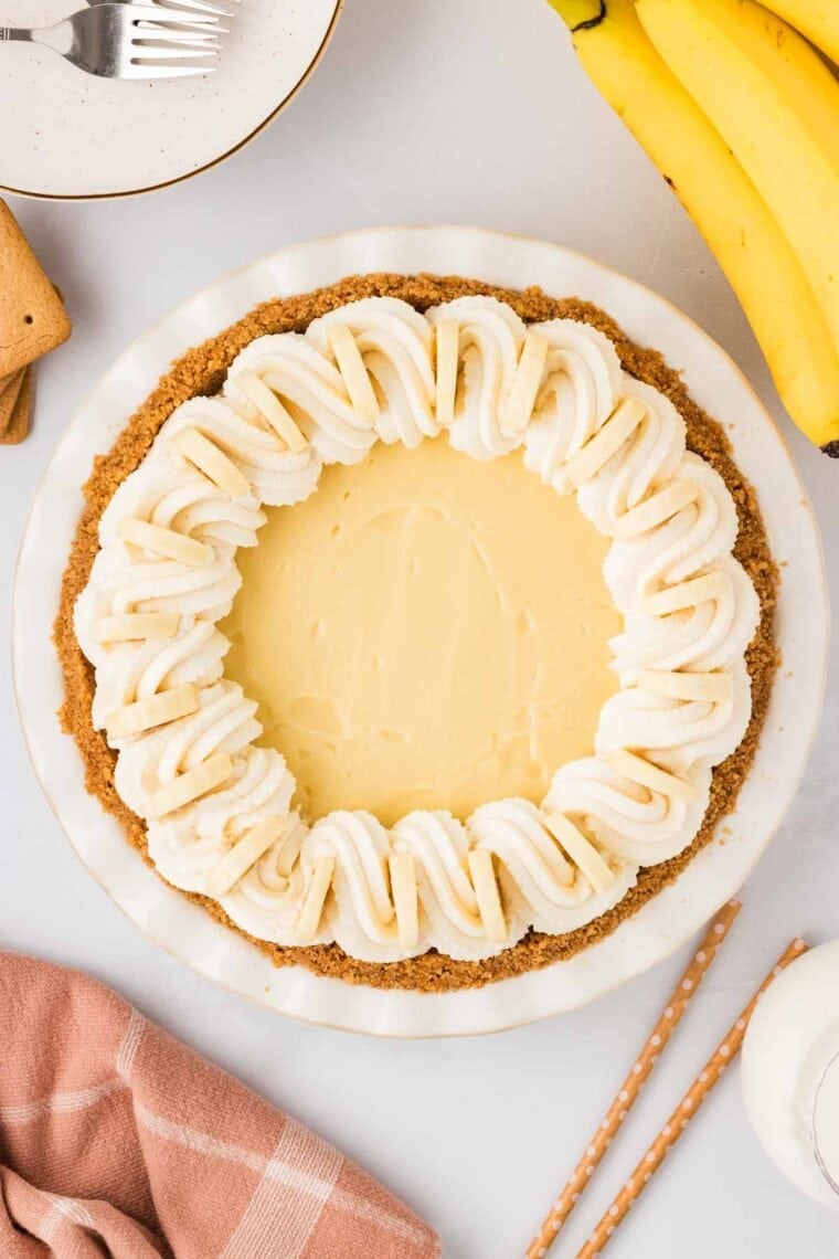 Banana cream pie with whipped cream piped around the edges and banana slices stuck inthe whipped ceam.