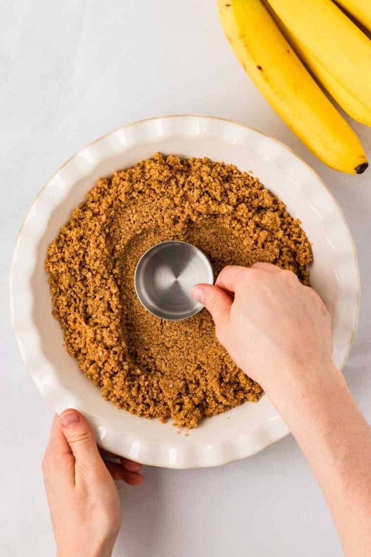Pressing graham cracker crust into a pie dish.
