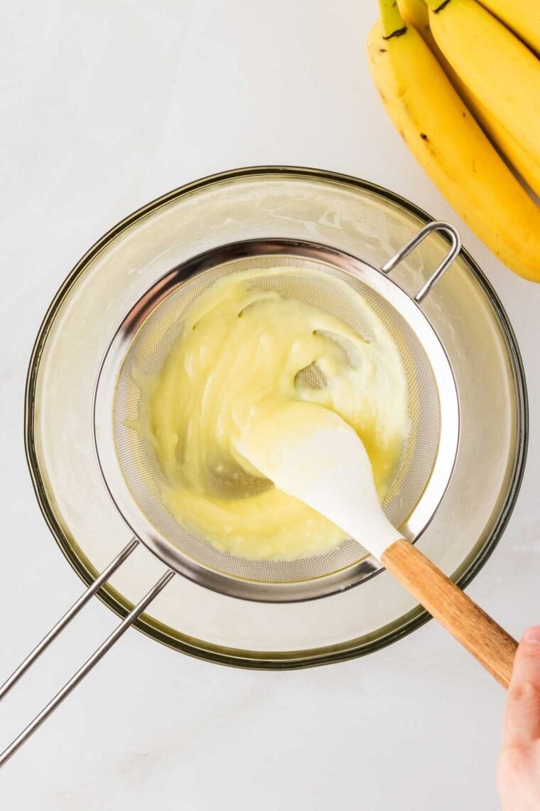 Pushing the filling for banana cream pie through a fine mesh sieve.