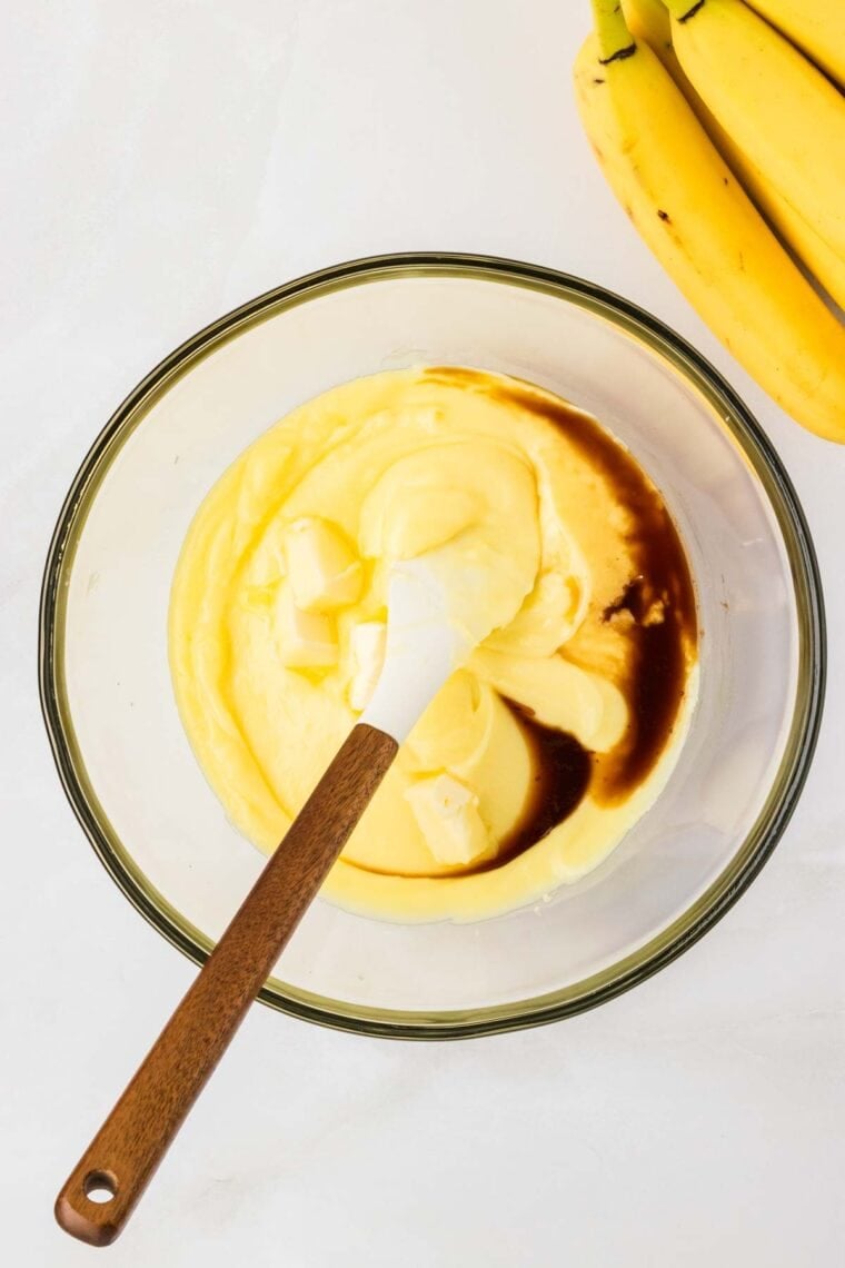 Stirring butter and vanilla into the filling for banana cream pie.