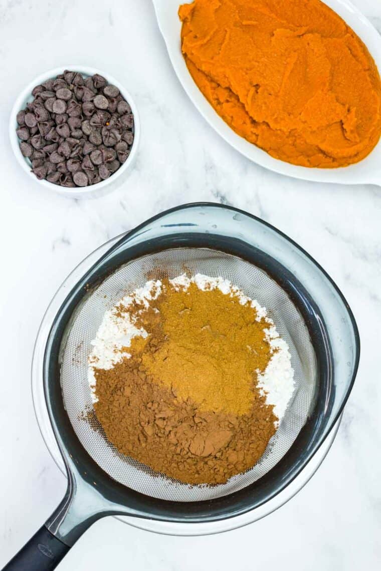 Sifting together flour, cocoa powder, pumpkin pie spice, baking soda, and salt.
