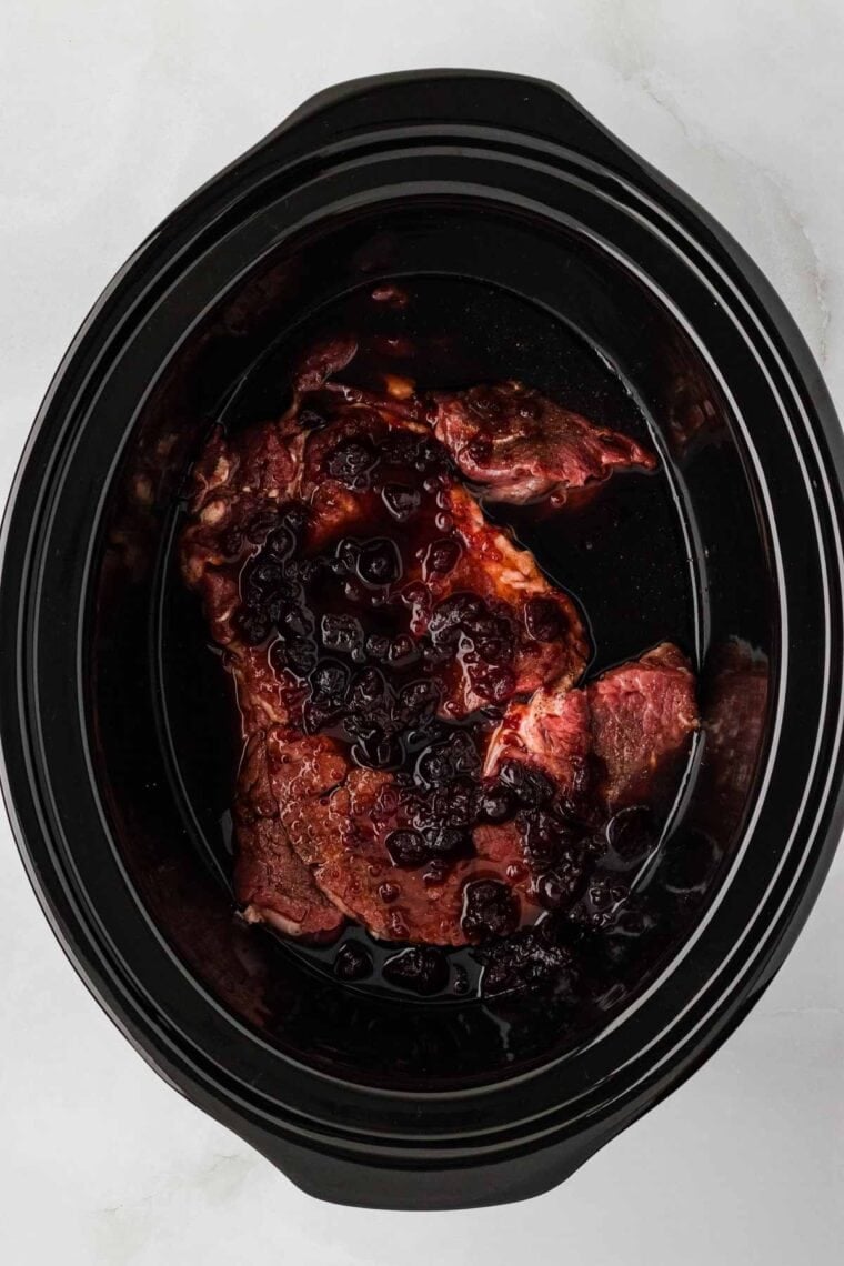 Slow cooker balsamic beef is the answer to your holiday hosting dreams, delivering melt-in-your-mouth beef in a tangy, subtly sweet sauce. Chuck roast in a crockpot covered with a sauce of cranberry sauce, balsamic vinegar, and red wine poured over it.