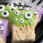 A cereal treat dipped in green chocolate and covered with candy eyes with text overlay that says "Monster Rice Krispie Treats".