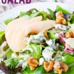 Salad greens topped with sliced pears, walnuts, and gorgonzola with text overlay that says "Poached Pear Salad".