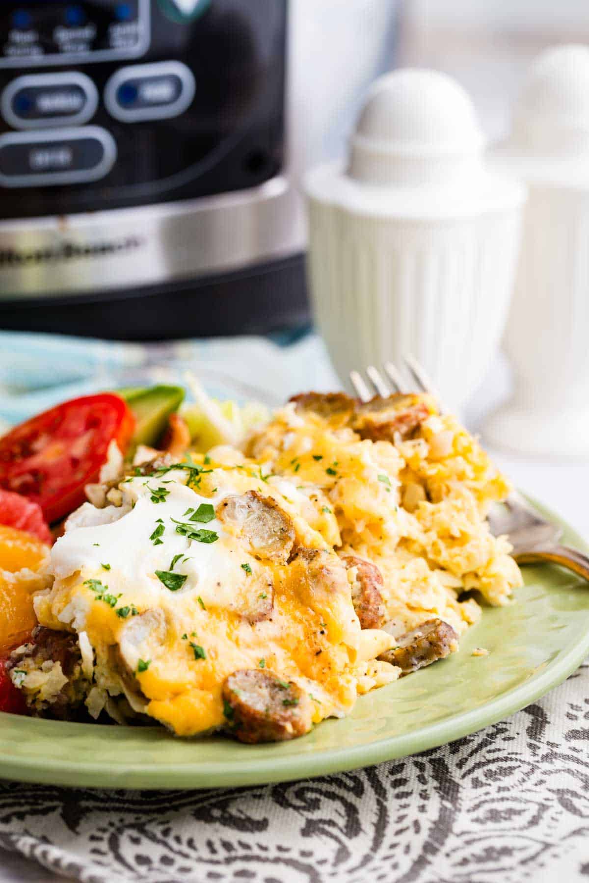 Cauliflower hash brown casserole served on a plate with a slow cooker behind it.