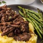 Slow cooker balsamic beef served over polenta with green beans.