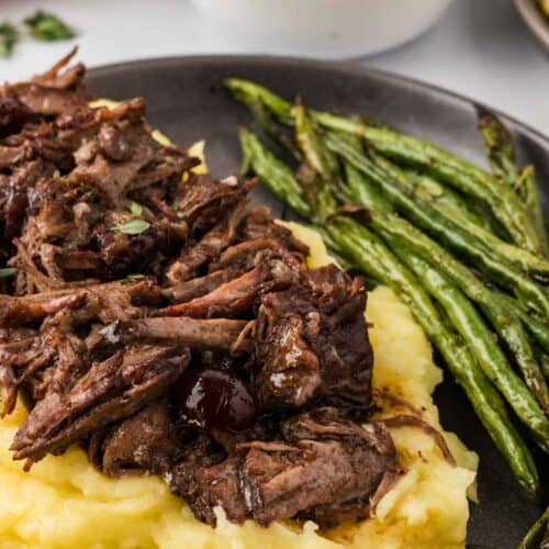 Slow cooker balsamic beef served over polenta with green beans.