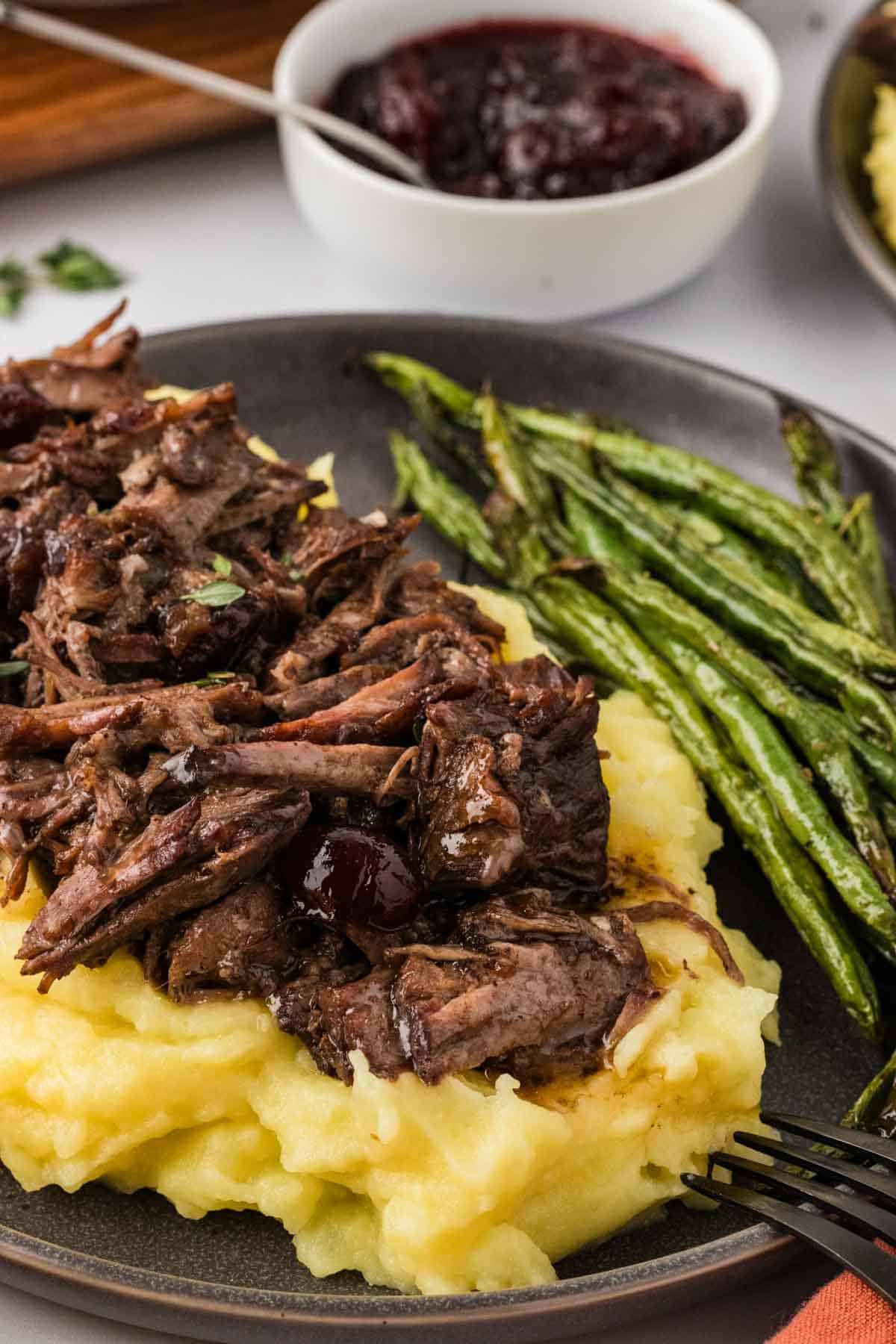 Slow cooker balsamic beef is the answer to your holiday hosting dreams, delivering melt-in-your-mouth beef in a tangy, subtly sweet sauce. Slow cooker balsamic beef served over polenta with green beans.