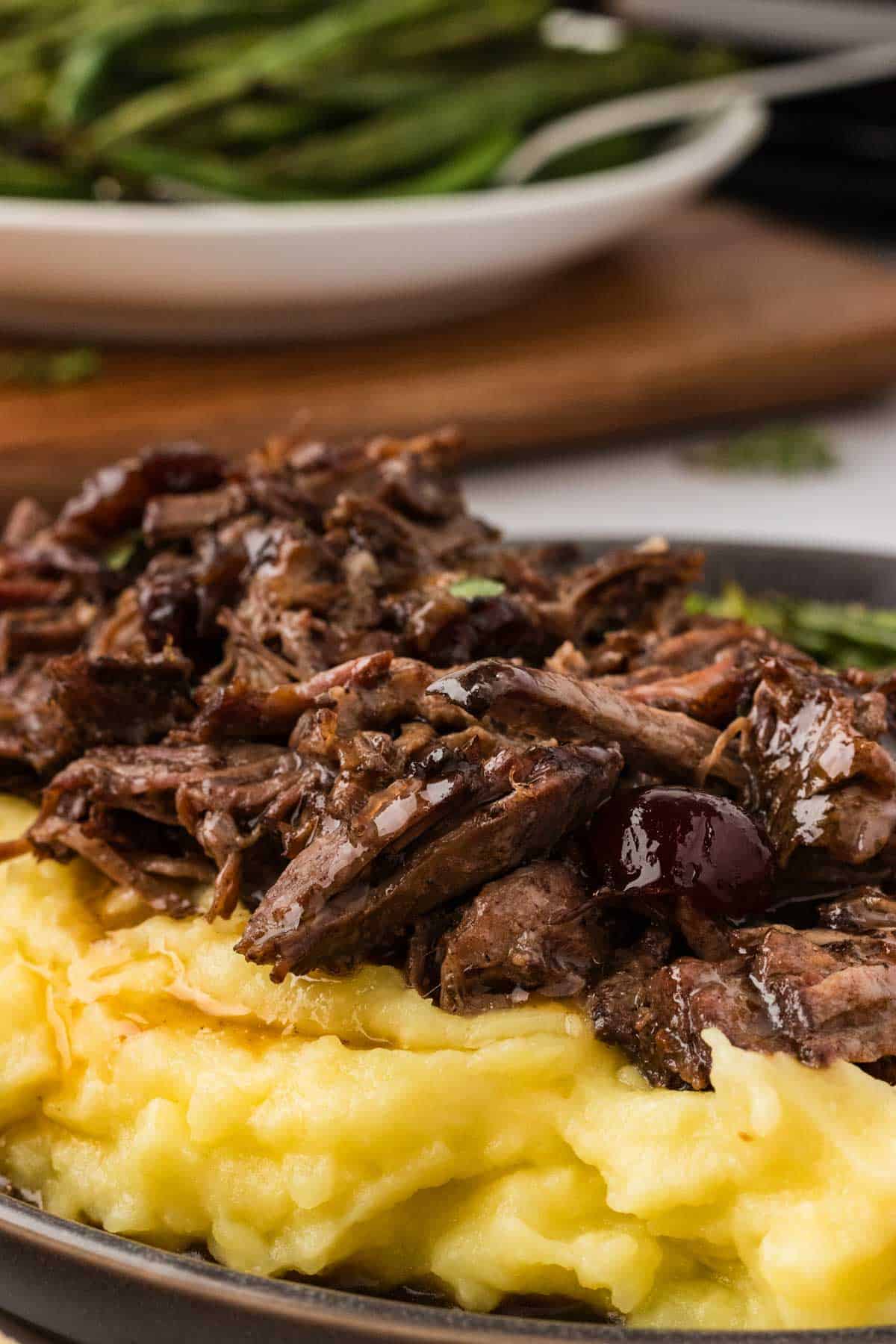 Slow cooker balsamic beef is the answer to your holiday hosting dreams, delivering melt-in-your-mouth beef in a tangy, subtly sweet sauce. Close-up image of slow cooker cranberry balsamic beef served over polenta.