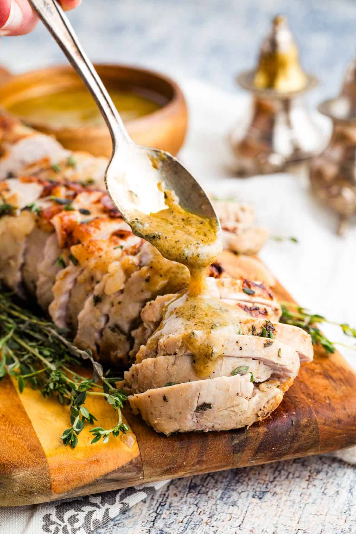 This bourbon pork tenderloin delivers tender, juicy meat with a mouthwatering maple-bourbon glaze. It'll change the way you think about pok! Spooning bourbon glaze over sliced pork tenderloin on a cutting board.