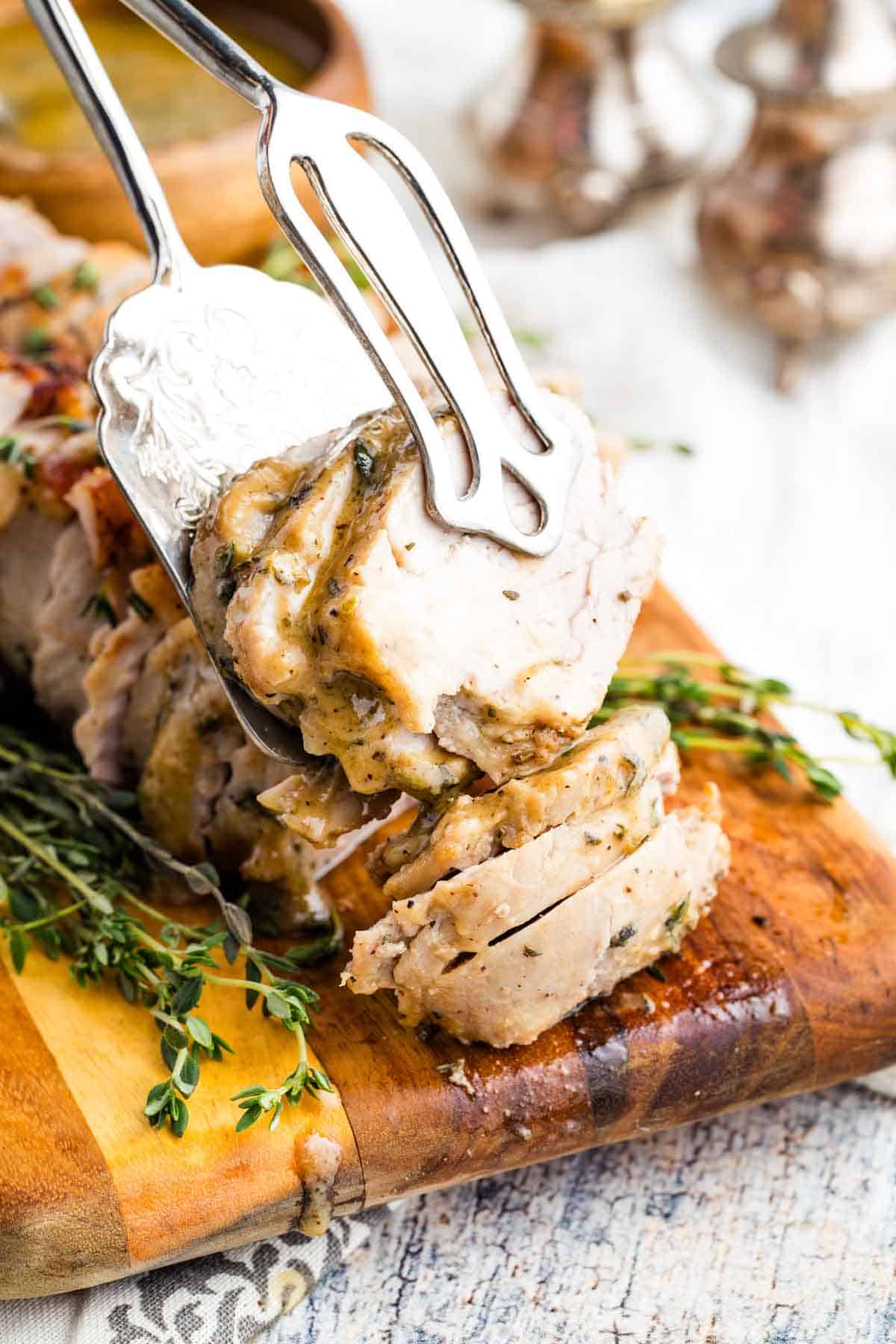 This bourbon pork tenderloin delivers tender, juicy meat with a mouthwatering maple-bourbon glaze. It'll change the way you think about pok! Serving tongs picking up slices of bourbon pork tenderloin.
