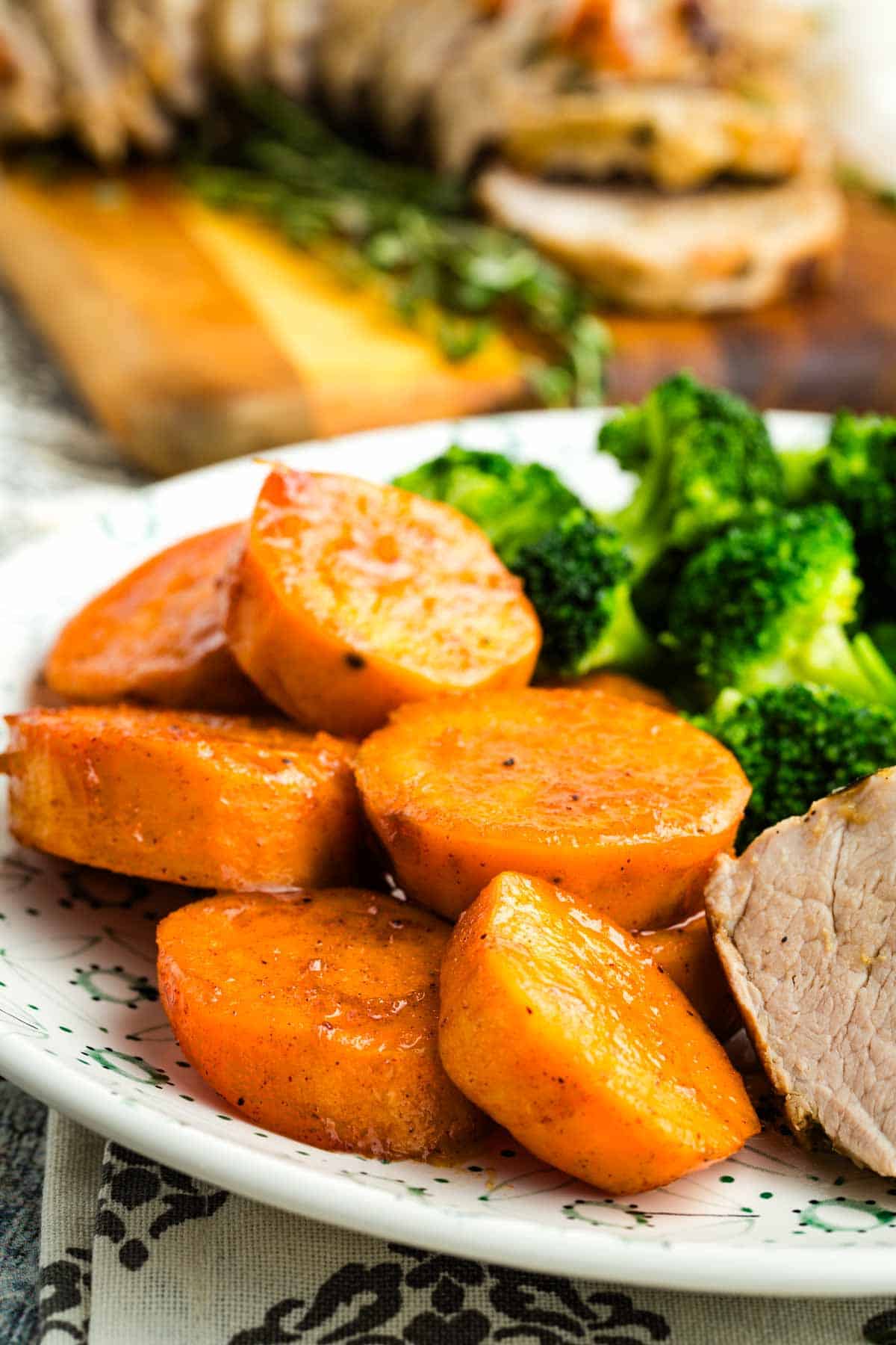 Candied sweet potatoes on a plate with meat and broccoli.
