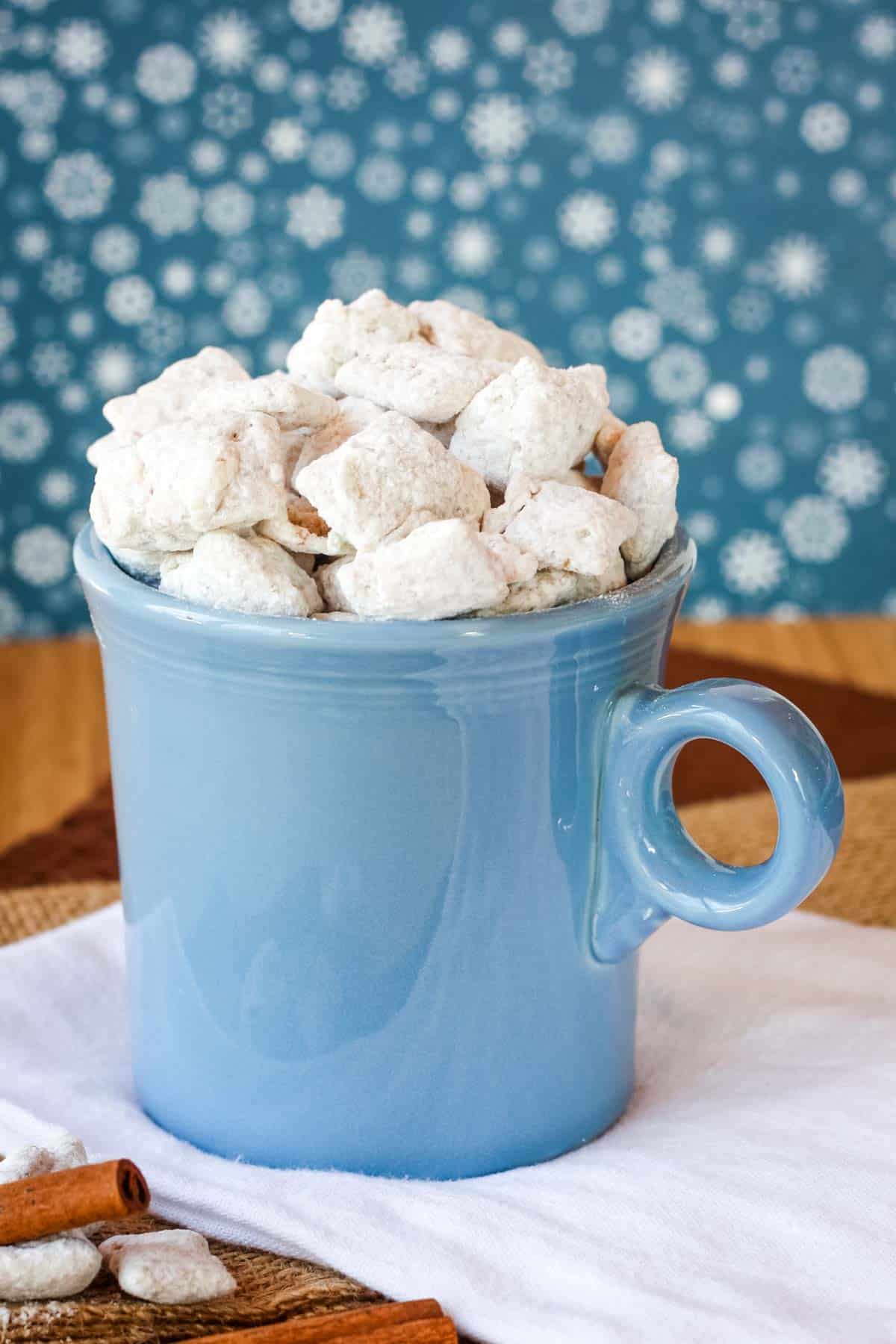 A blue mug full of Chai White Chocolate Chex snack mix.