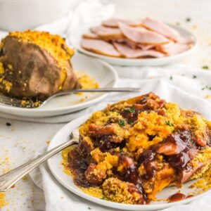A stuffed sweet potato covered with barbecue sauce on a plate.