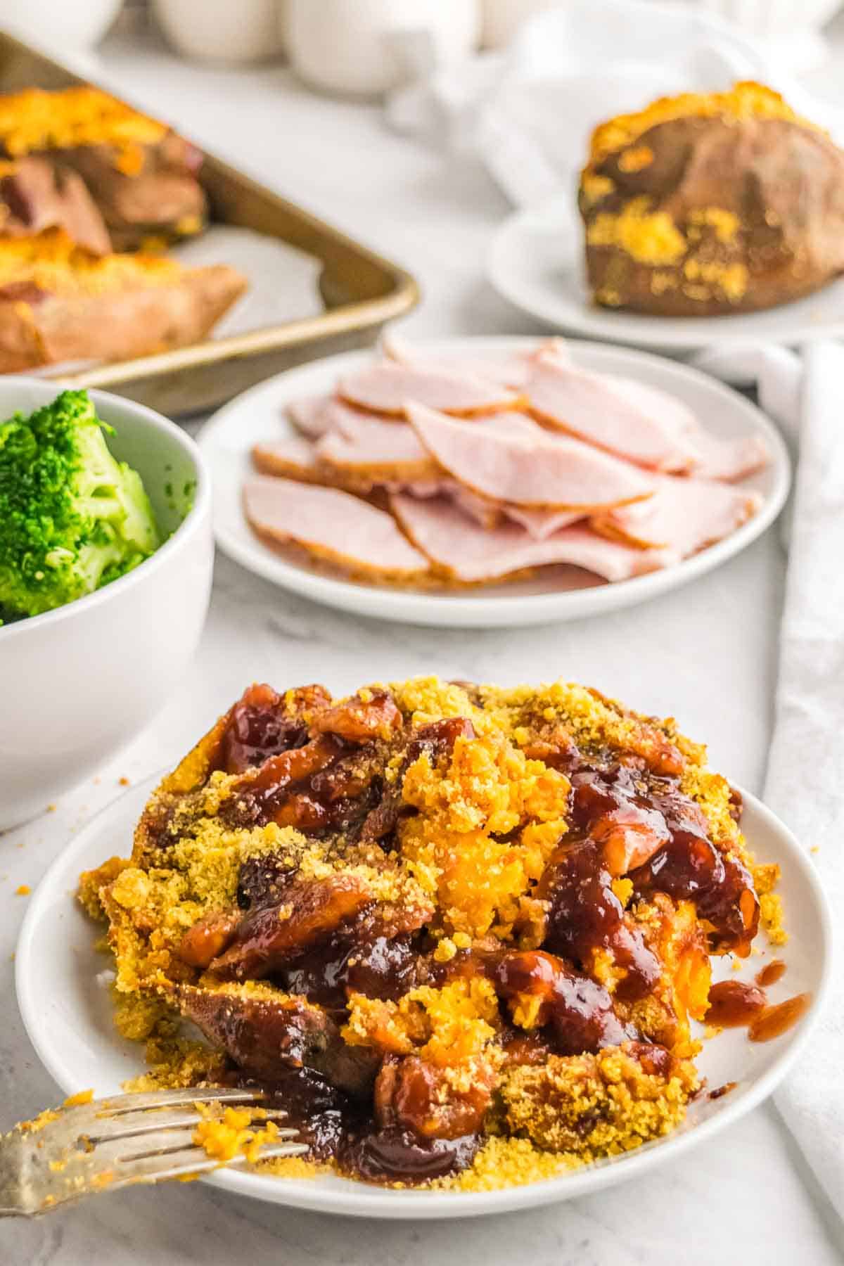 A cranberry barbecue stuffed sweet potato with crumb topping and a drizzle of sauce on a plate.