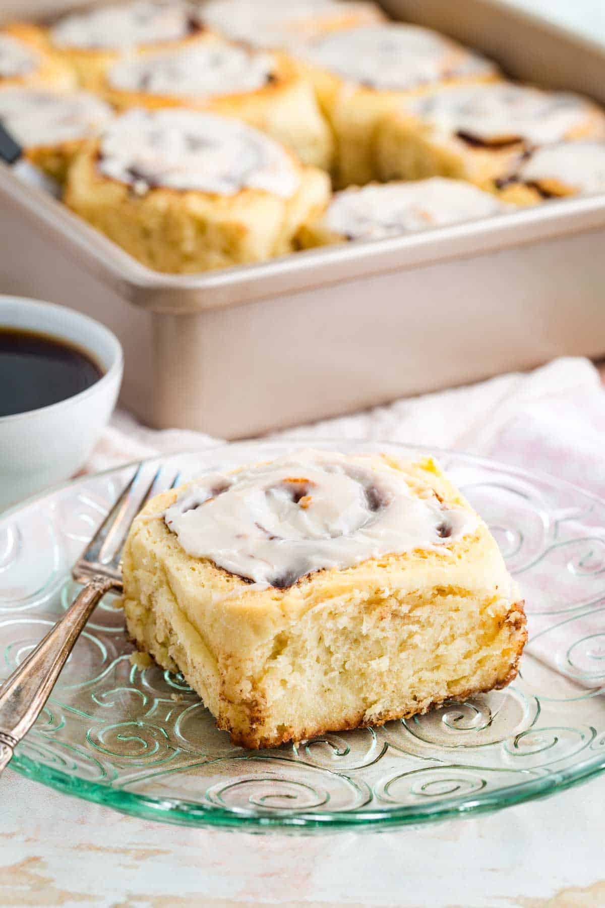 A chocolate cinnamon roll on a plate with a fork.