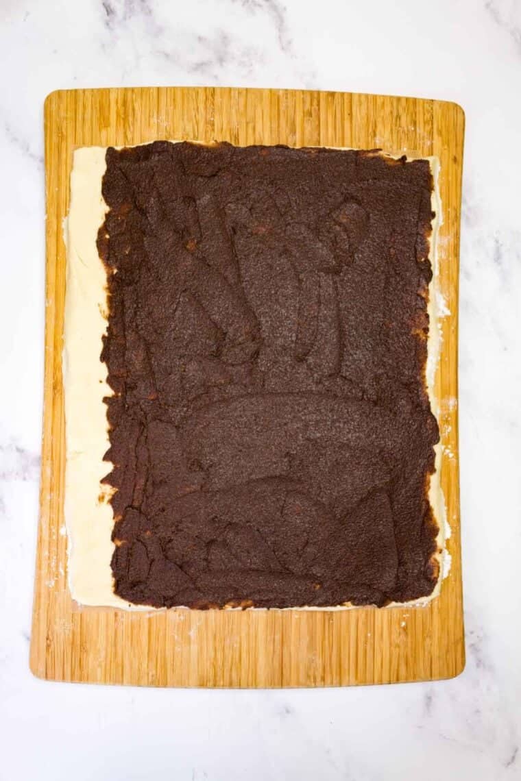 Chocolate-cinnamon paste spread over cinnamon roll dough.