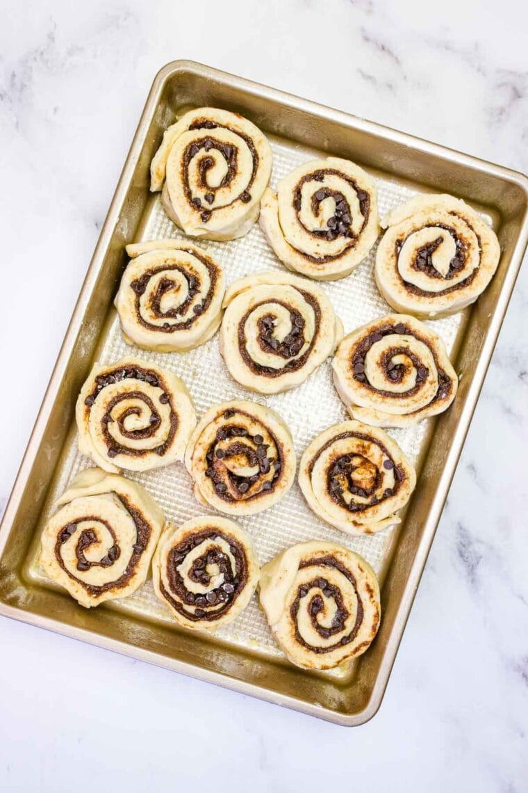 Chocolate cinnamon rolls arranged in a baking pan.