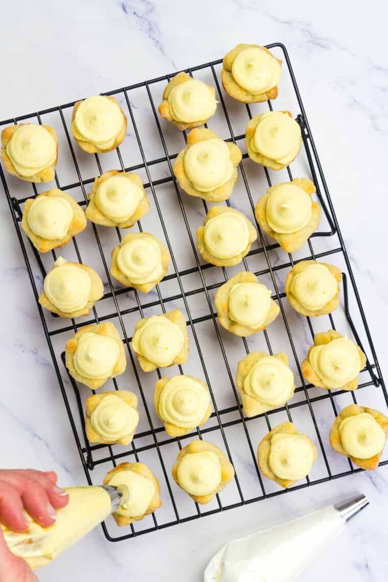 Piping eggnog pudding mixture into mini pie shells.