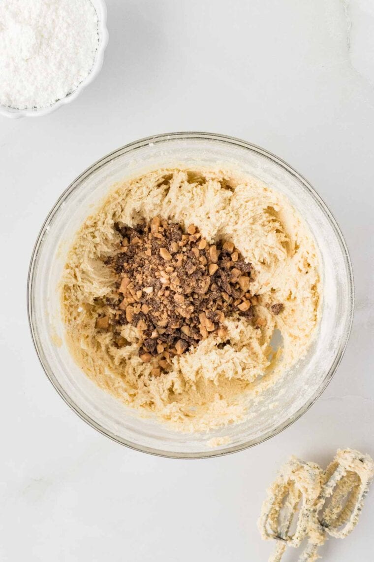 Adding toffee bits to almond snowball cookie dough.