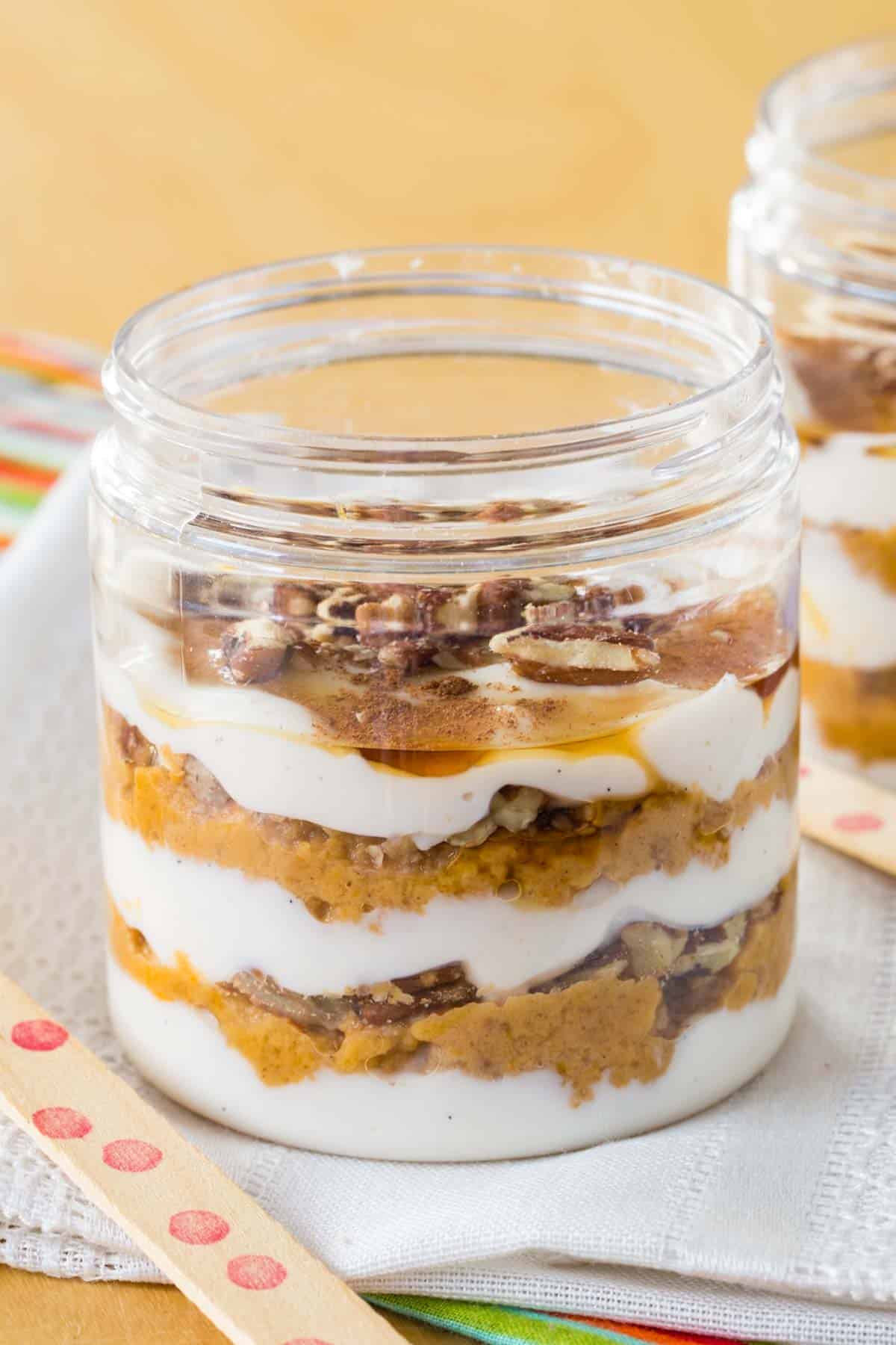 A jar with layers of Greek yogurt, pumpkin pie filling, maple syrup, and pecans.