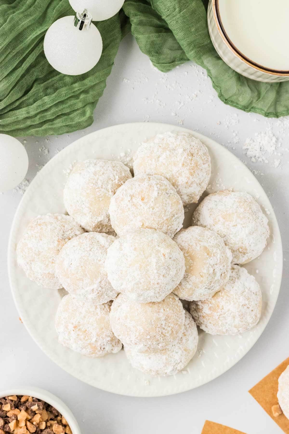 Overhead image of a pile of toffee almond snowball cookies on a plate.
