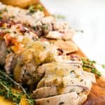 Sliced pork with sauce on a cutting board with text overlay that says "Bourbon Pork Tenderloin".