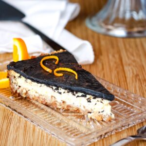 Chocolate orange tart with a crunchy crust and orange zest garnish, served on a glass platter.