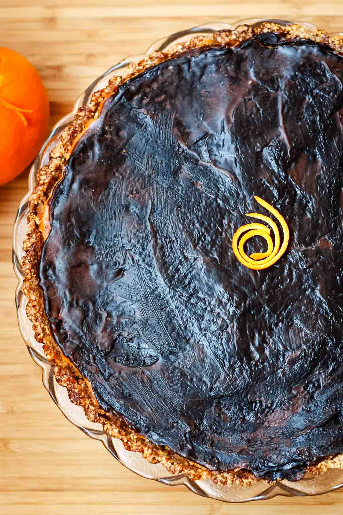 Overhead view of a tart with a shiny chocolate shell on top.