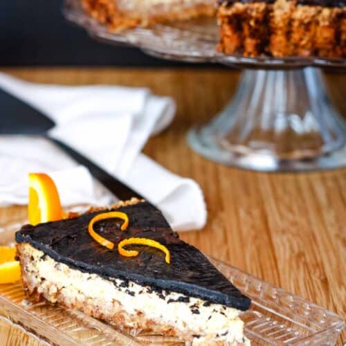 A slice of orange chocolate tart with a creamy filling and chocolate shell topping on a rectangular glass dish.