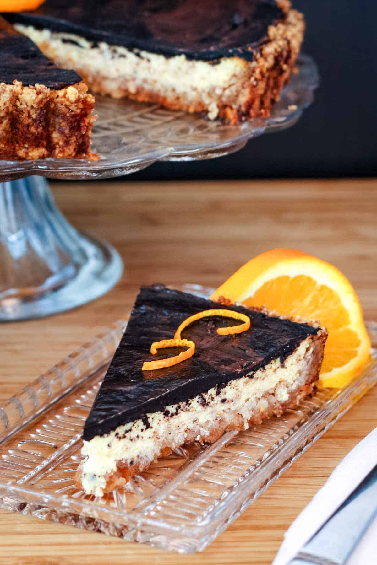 A wedge of gluten free orange chocolate tart on a crystal dish.