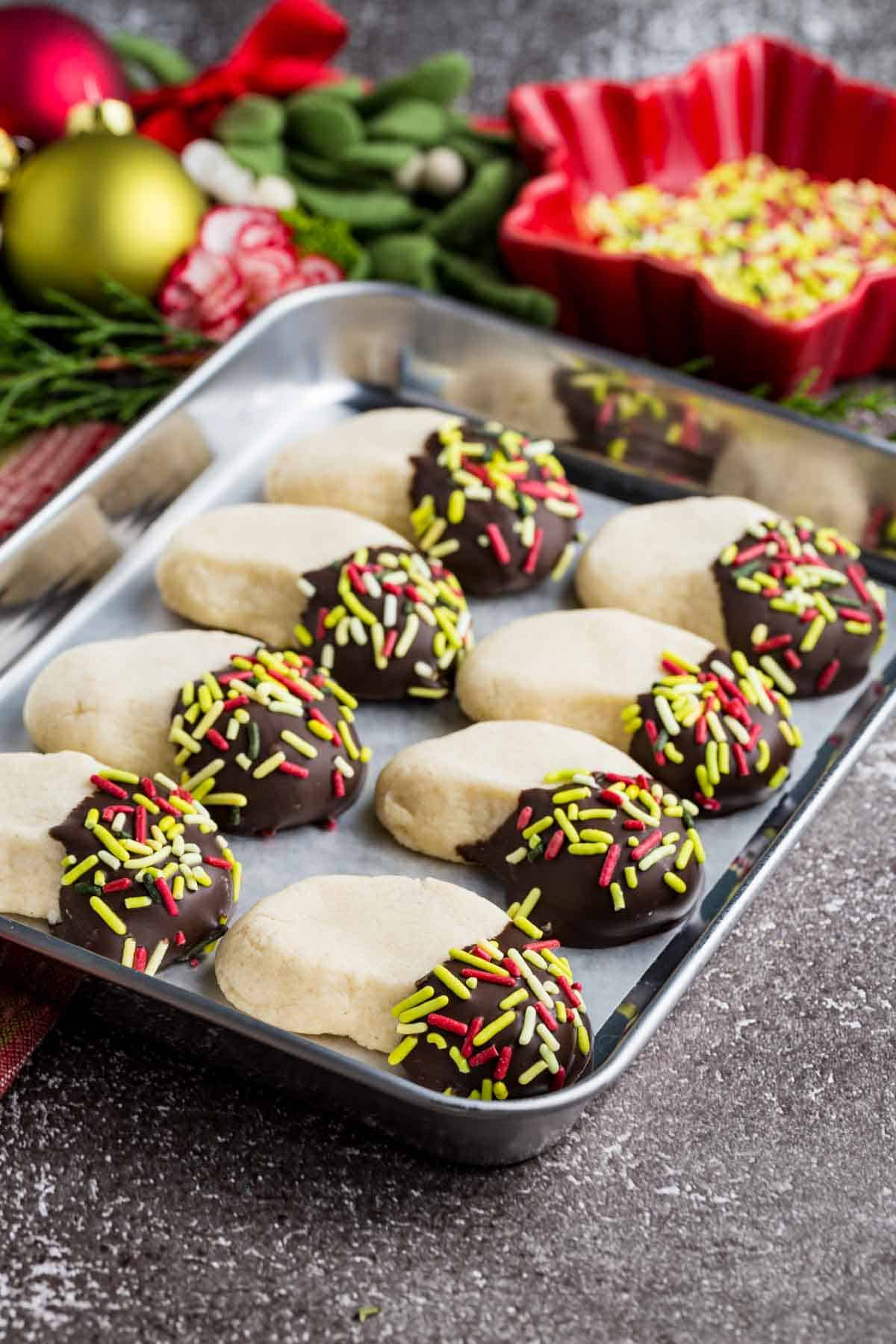 Make tender, buttery gluten-free almond crescent cookies dipped in chocolate! They're the easiest Christmas cookies with only 4 ingredients. Almond crescent cookies with one end covered in chocolate and sprinkles on a small sheet pan.